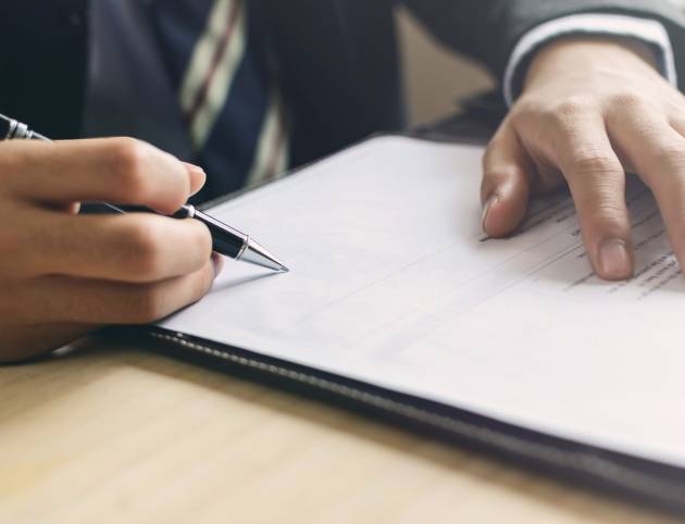 Close up Human Hand Signing on Formal Paper at the workplace