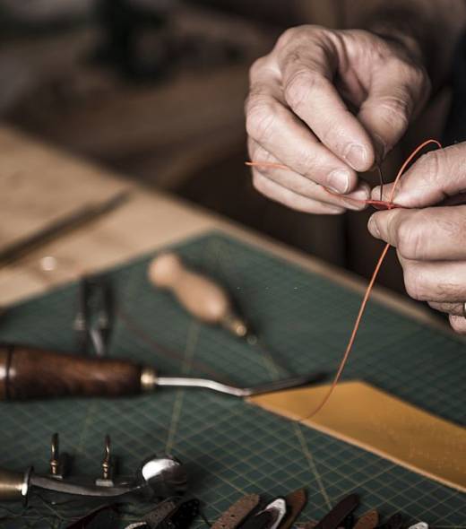 Close up shoot of an artisan working with leather in his laboratory.