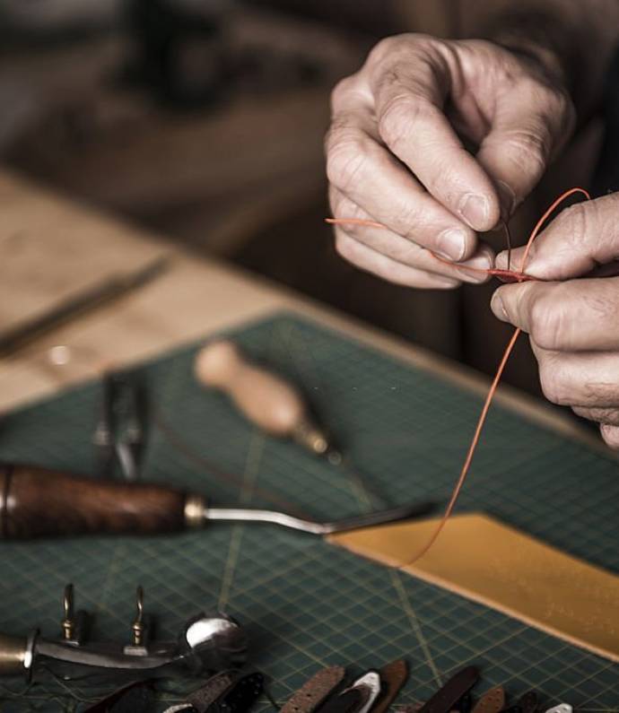 Close up shoot of an artisan working with leather in his laboratory.